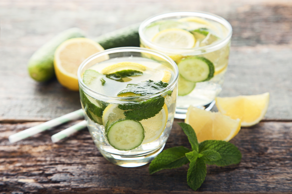 Lemonade with cucumbers, lemons and mint leafs in glasses on wooden table