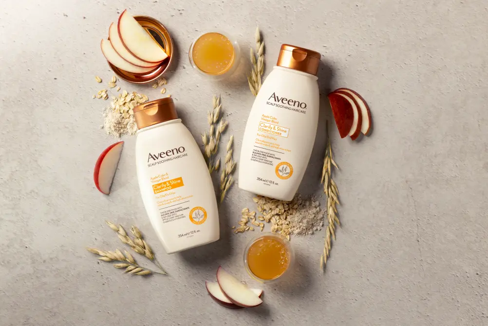 Set of AveenoÂ® Clarity & Shine Shampoo and Conditioner surrounded by nourishing hair ingredients