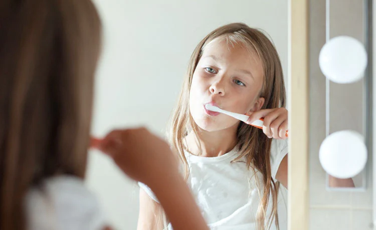Girl Brushing her Teeth in Mirror