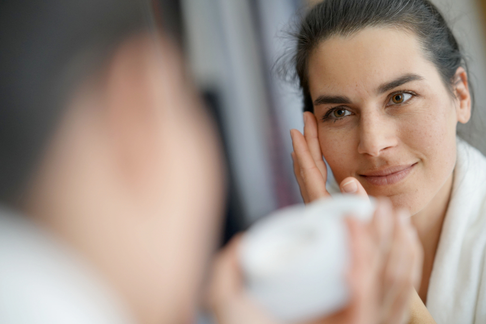 Woman applying moisturizer to improve the look of dark spots